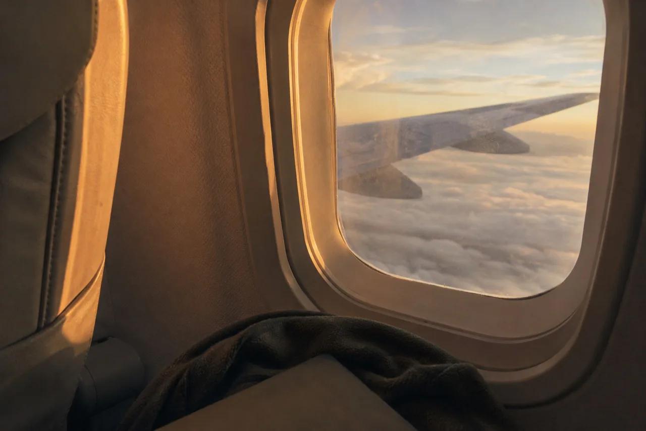 Hublot d’avion, aile au-dessus des nuages à l’heure dorée