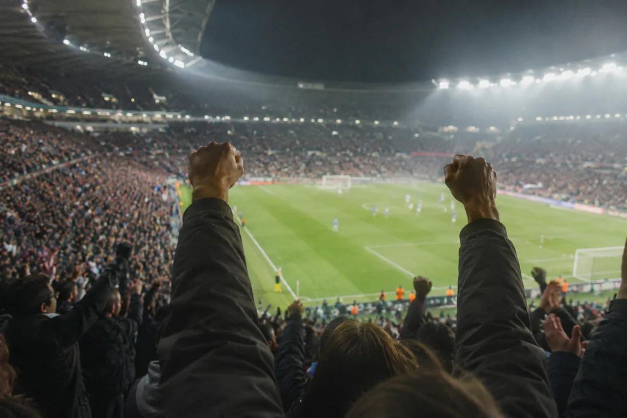 Spectateurs bras levés dans un stade pendant un match
